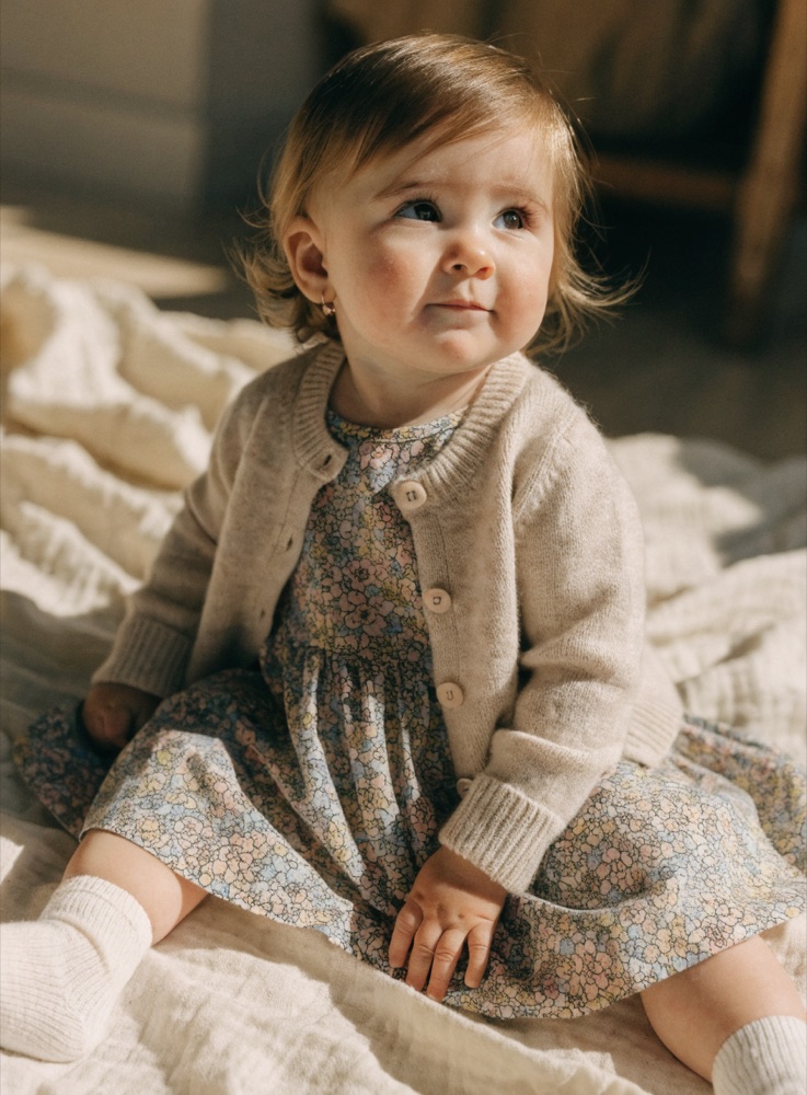 Bebê com vestido floral e tricô